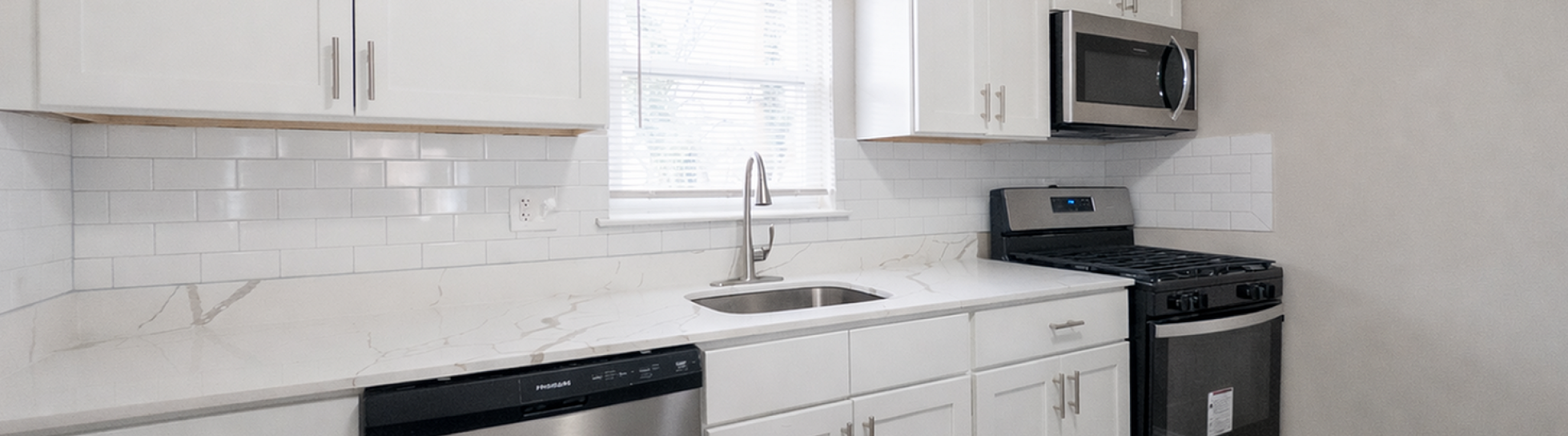 Modern kitchen featuring sleek white cabinets, stainless steel appliances, and elegant subway tile backsplash.