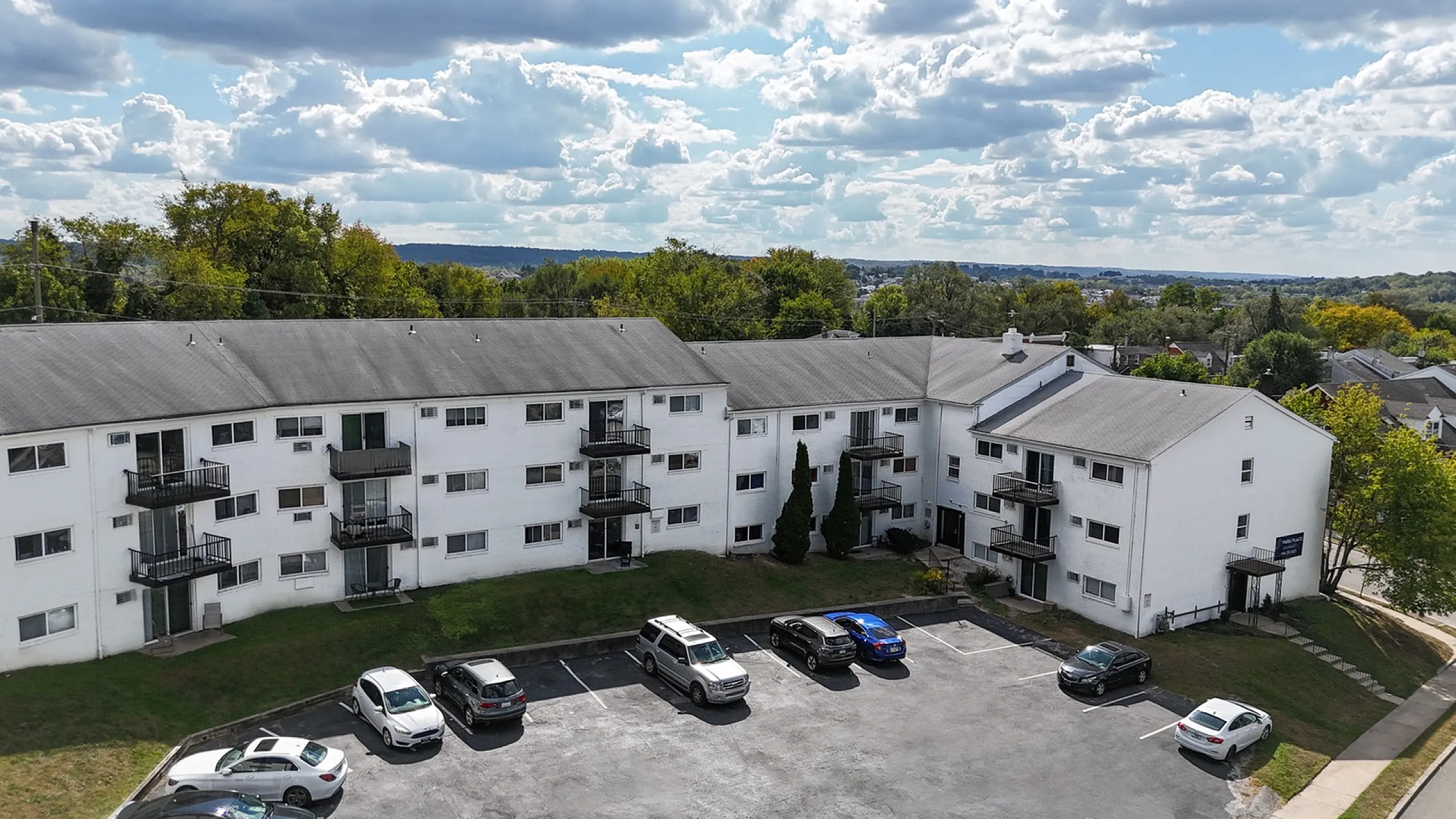 Park Place Apartments in Norristown PA, 3 story white brick apartment building with balconies and a parking lot
