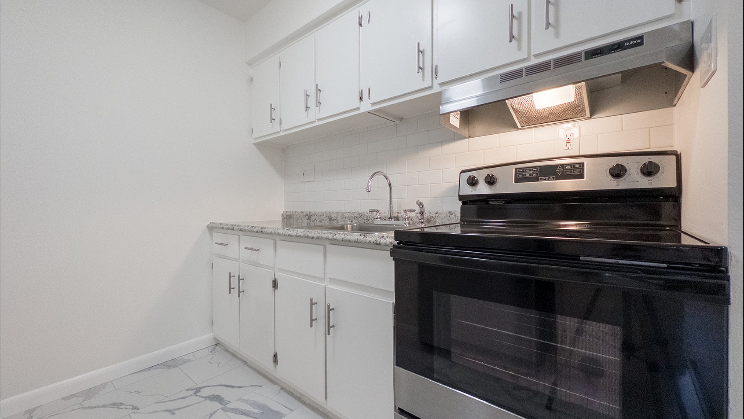 Modern kitchen featuring sleek white cabinets, granite countertops, and a contemporary stainless steel stove.