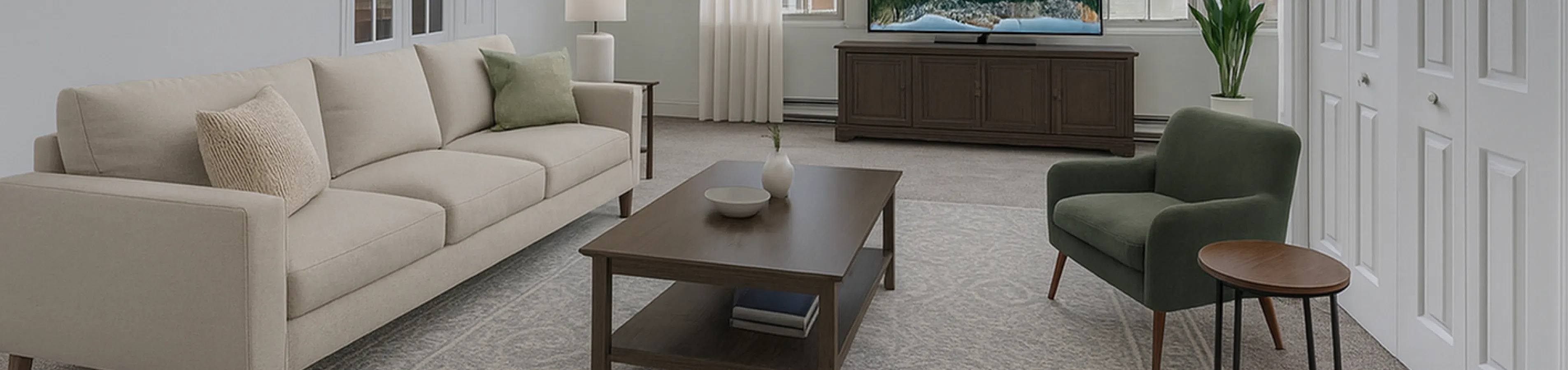 Bright and spacious living room with vaulted ceiling, elegant beige sofa, and large windows for natural light.