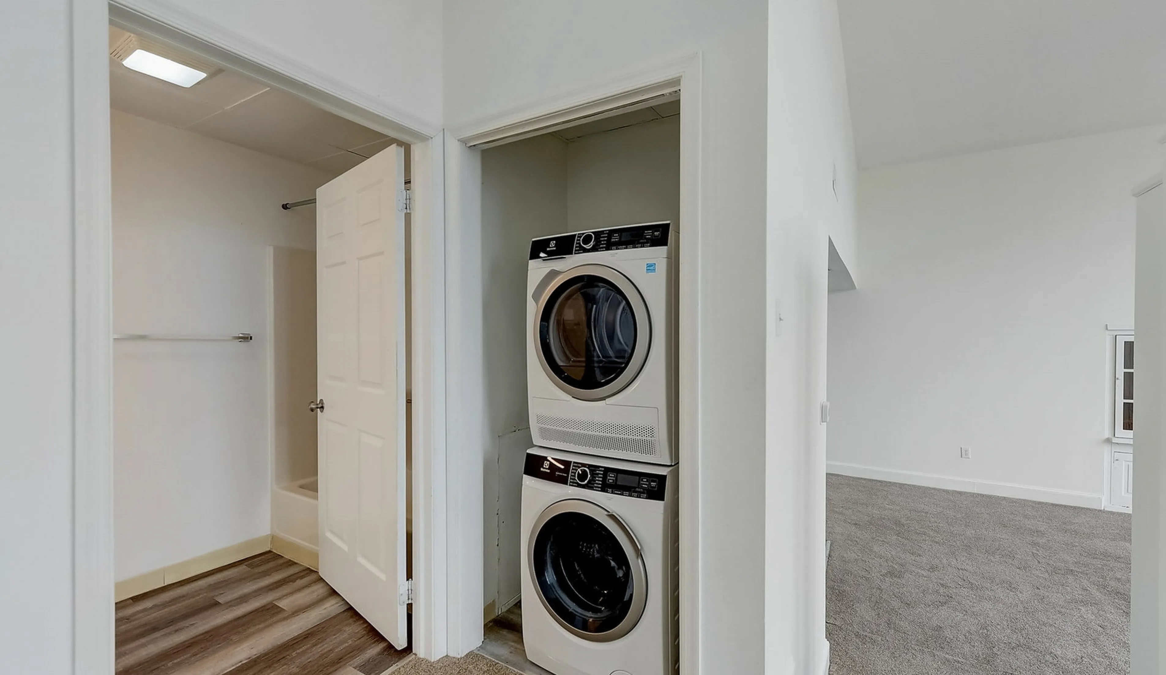 Modern apartment interior featuring a convenient washer-dryer combo in a bright hallway, adjacent to a bathroom and living area.