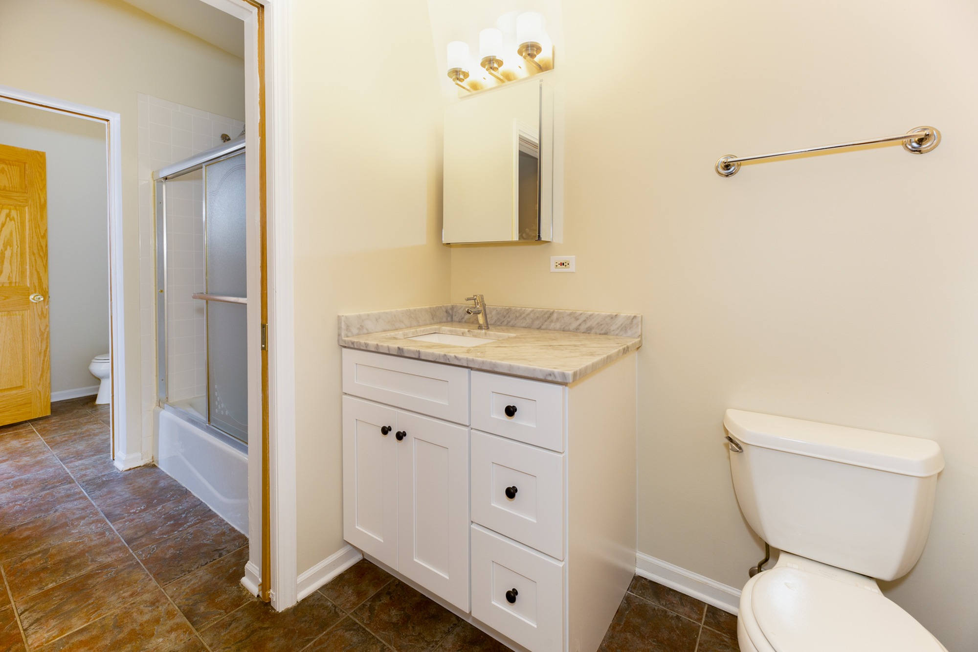 An upgraded one and a half bath with a white vanity, granite countertop and white bathtub.