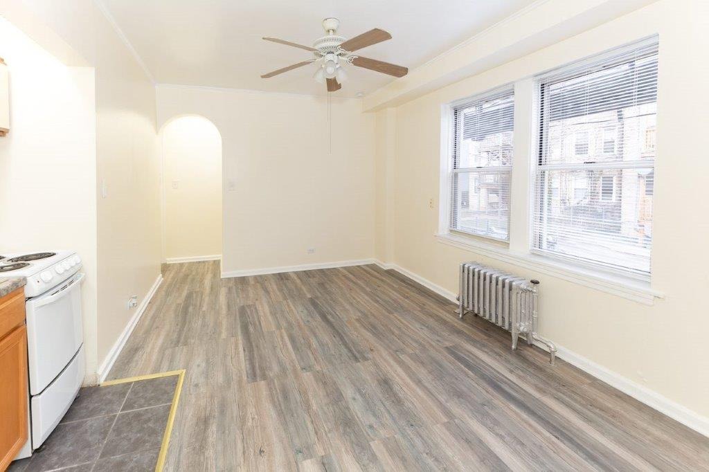 Apartment 107 Living Room with grey floor and sunny windows.