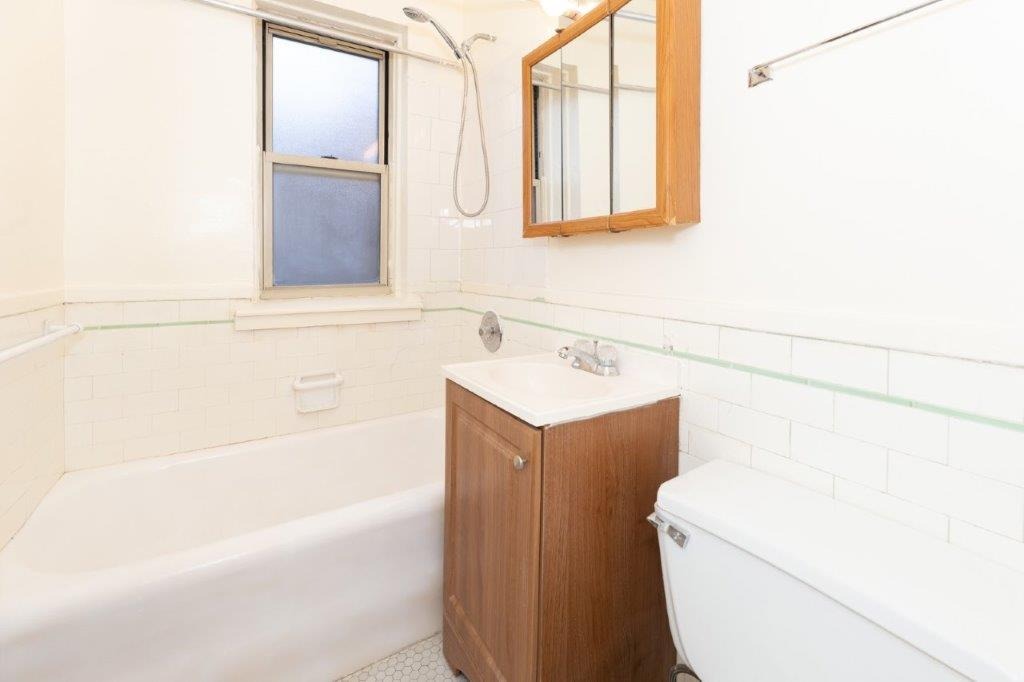 06 tier bathroom with wooden vanity and tub.
