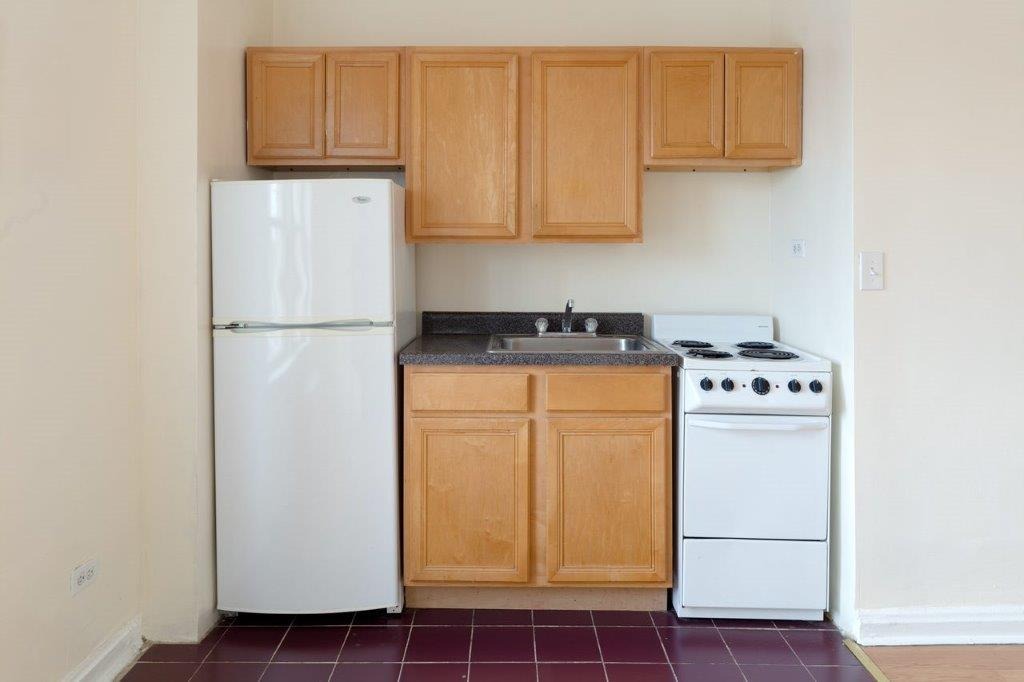 03 Tier Kitchen with wooden cabinets and white appliances.