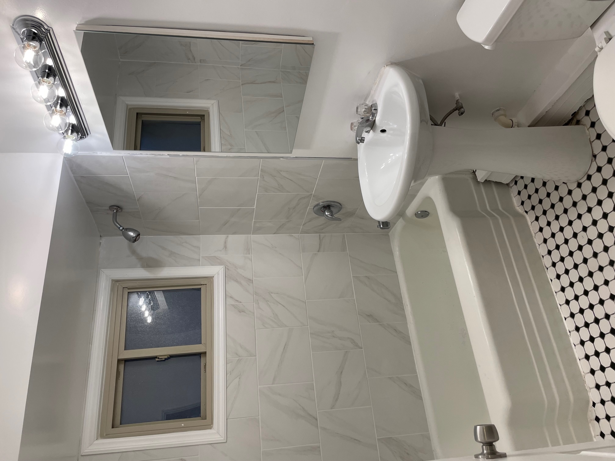 Bathroom with white pedestal sink, tub, and vintage charm.