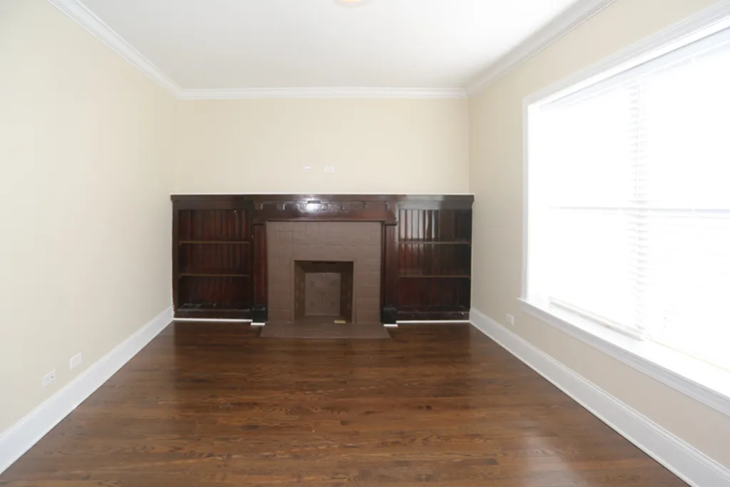 A living room with a dark brown decorative fireplace and bookshelves.