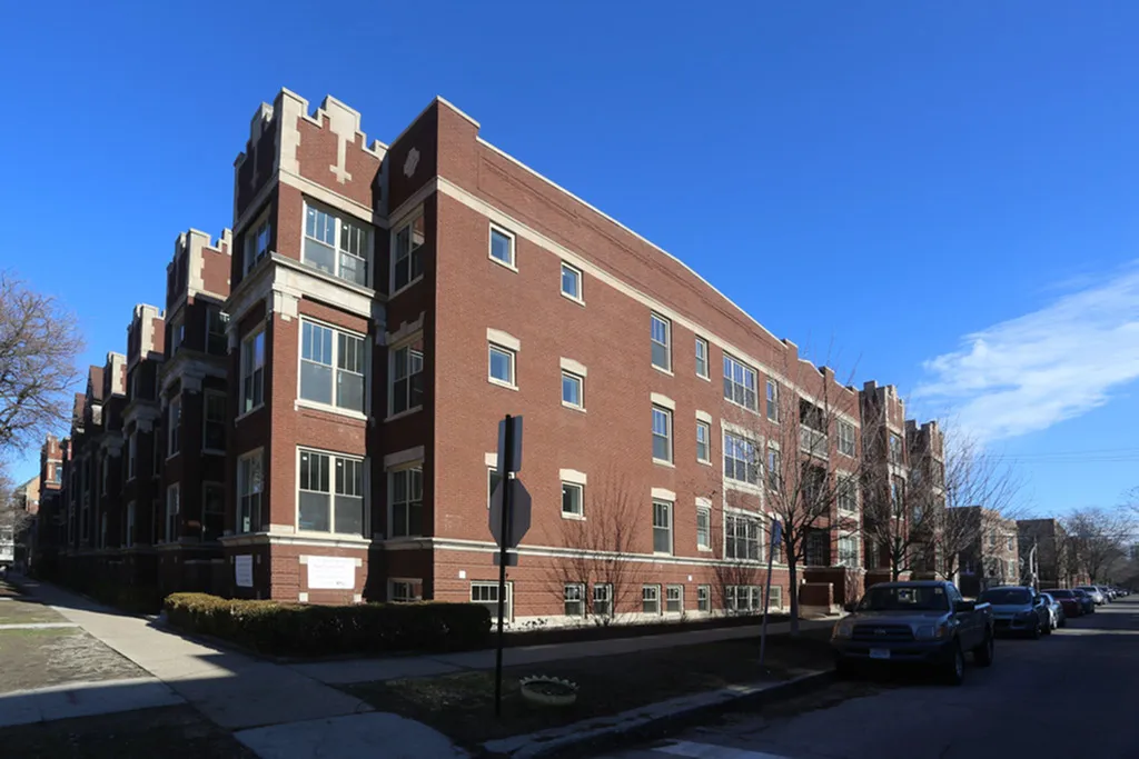 A handsome three story red brick apartment building under a cloudless blue sky.