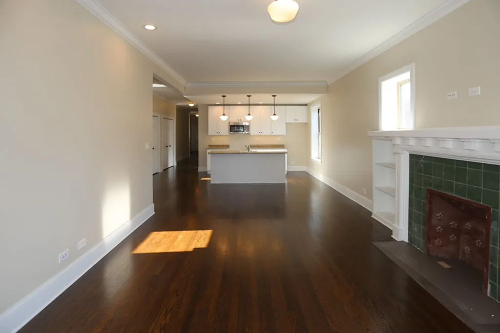 Open concept living / kitchen area with pendant lighting, hardwood floors, and a decorative fireplace.
