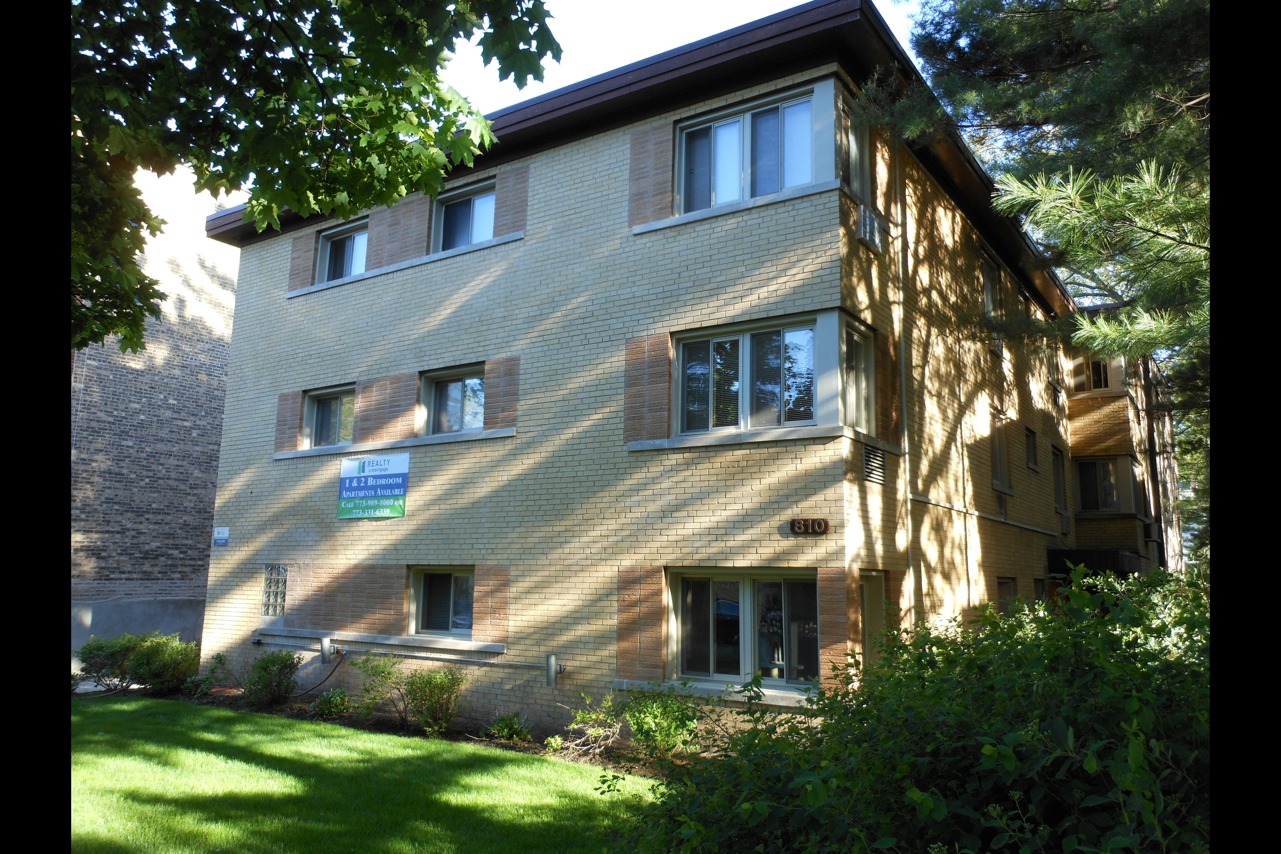 Exterior of 810 Seward an eleven unit three story mid century yellow brick building on a tree lined street in Evanston.