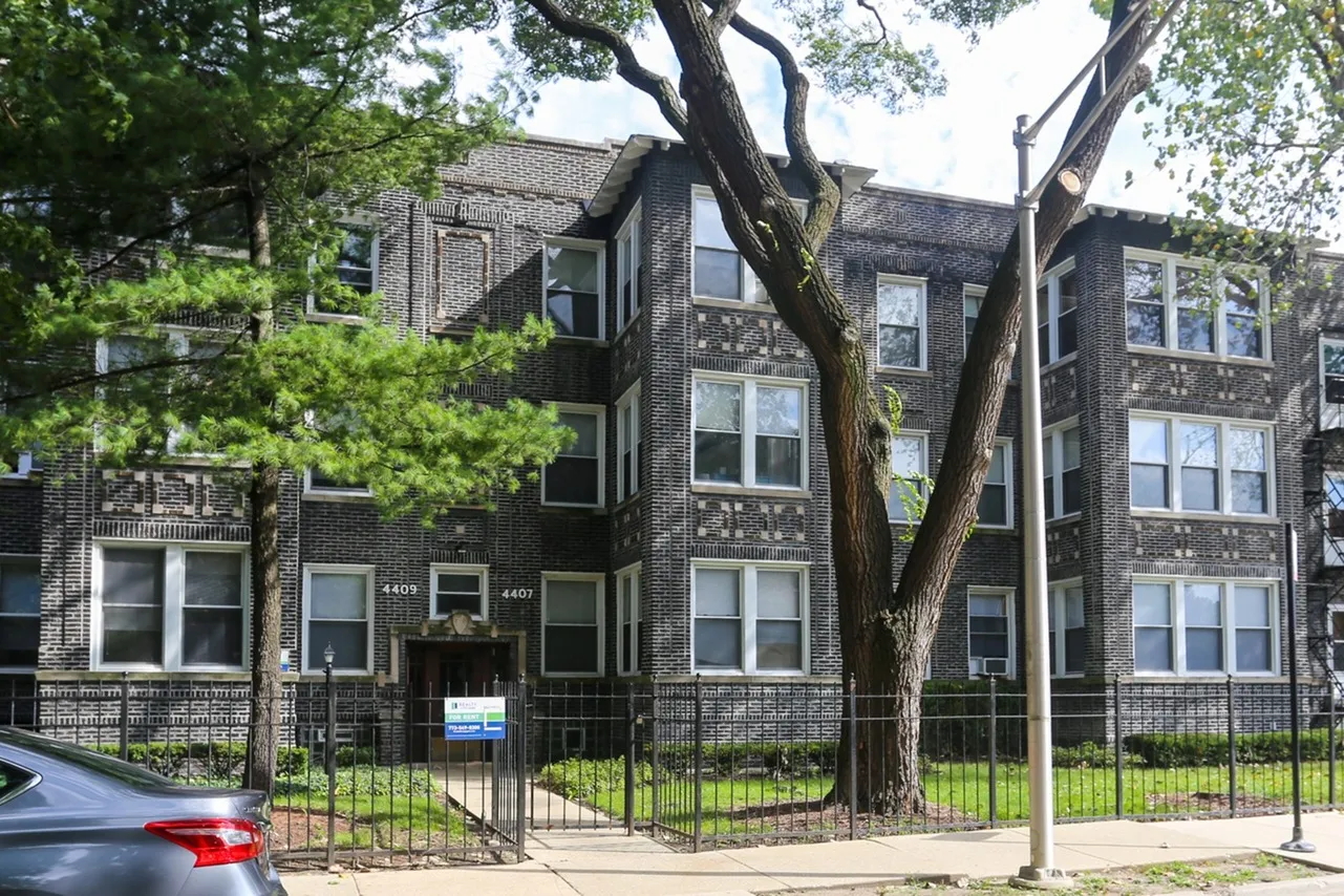 Exterior of 4407-09 North Malden a vintage thirty unit three story building with a grey brick exterior and mature trees in Sheridan Park.