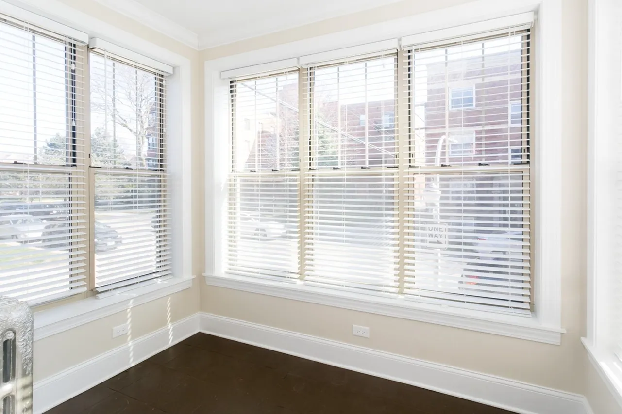 A sunroom with oversized windows on three sides and a dark brown floor.