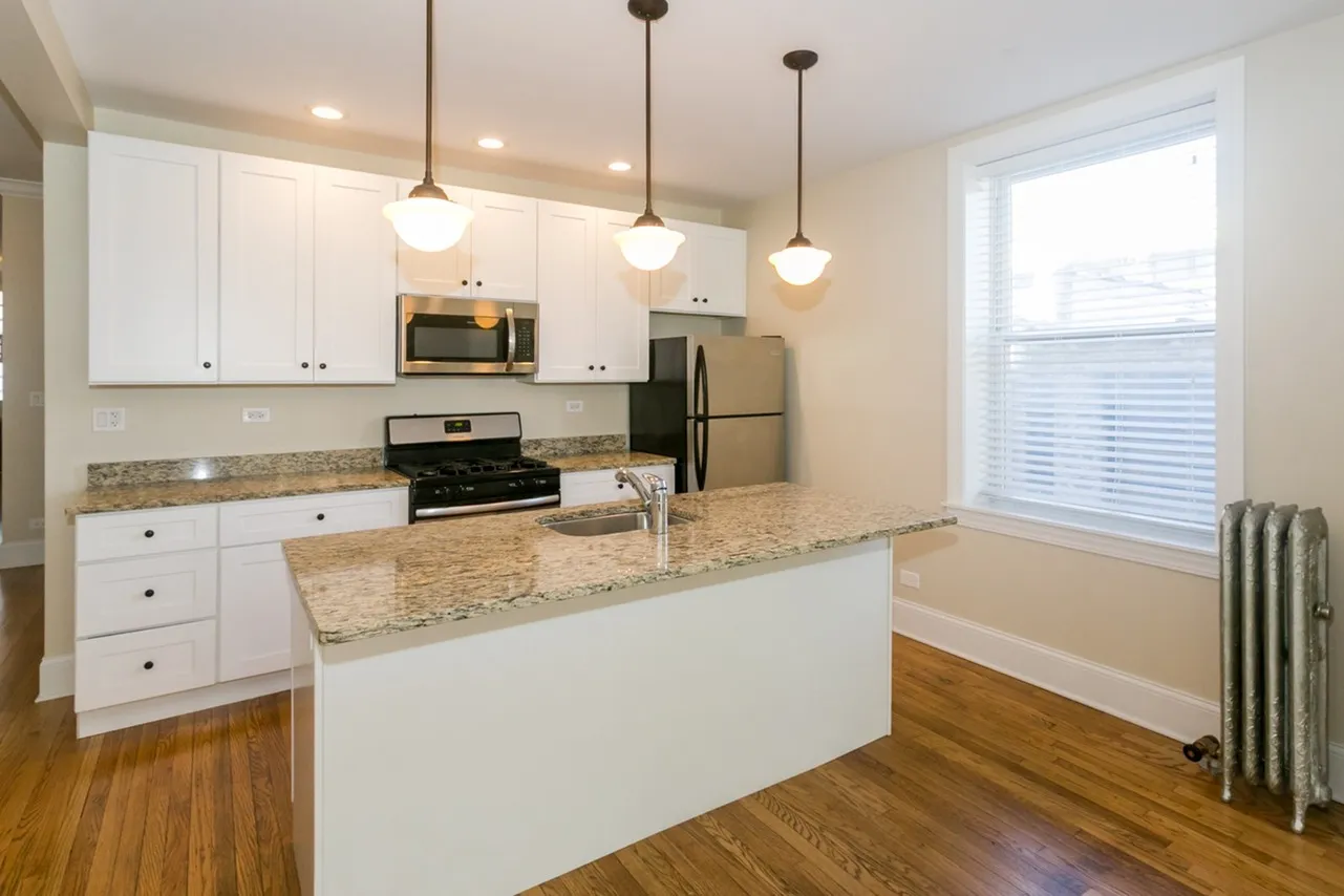 Upgraded open concept kitchen with white cabinets, pendant lighting, stainless appliances, granite tops, and a dishwasher.