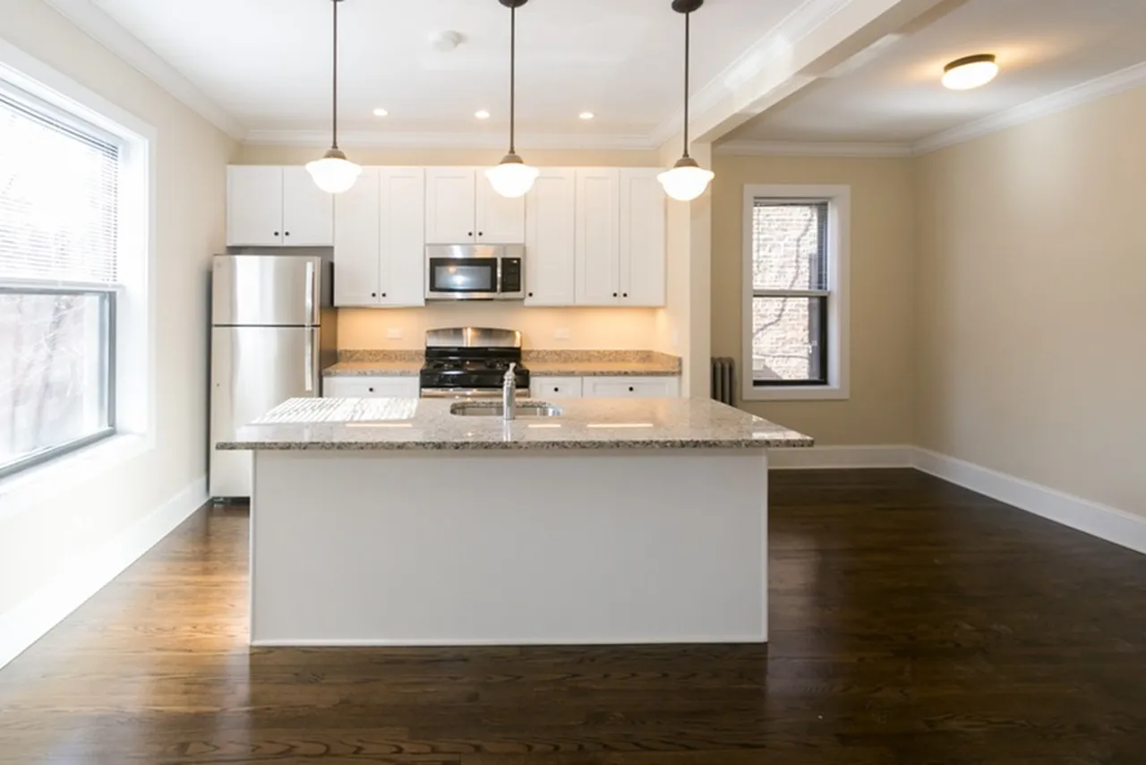 Upgraded open concept kitchen with white cabinets, pendant lighting, stainless appliances, and granite countertops.