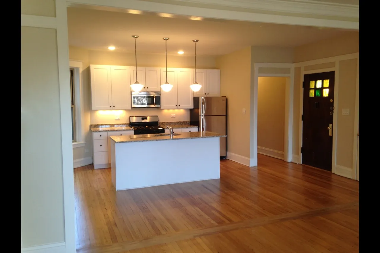 Open concept kitchen with pendant lighting, white cabinets, granite tops, and a dishwasher.