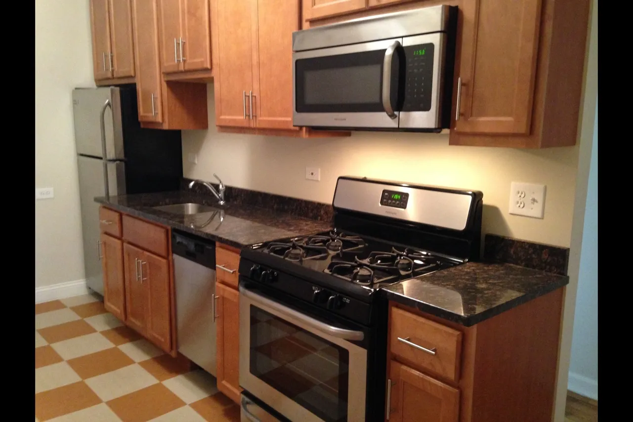 Kitchen with wooden cabinets, stainless steel appliances, and dark granite countertops.