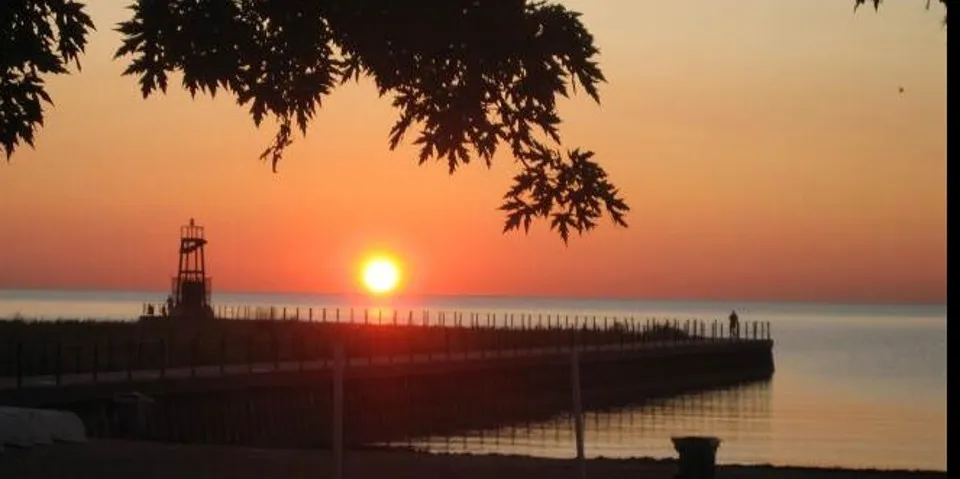 A bright orange sunset falling beyond the horizon on Lake Michigan.