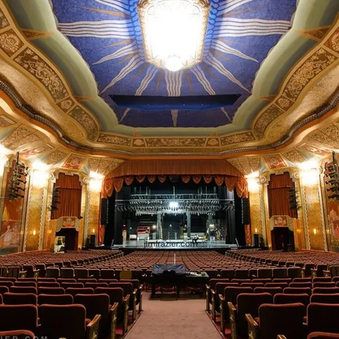 Paramount Theatre historic interior with dramatic plaster work, light sconces and a brightly lit blue ceiling in Aurora.