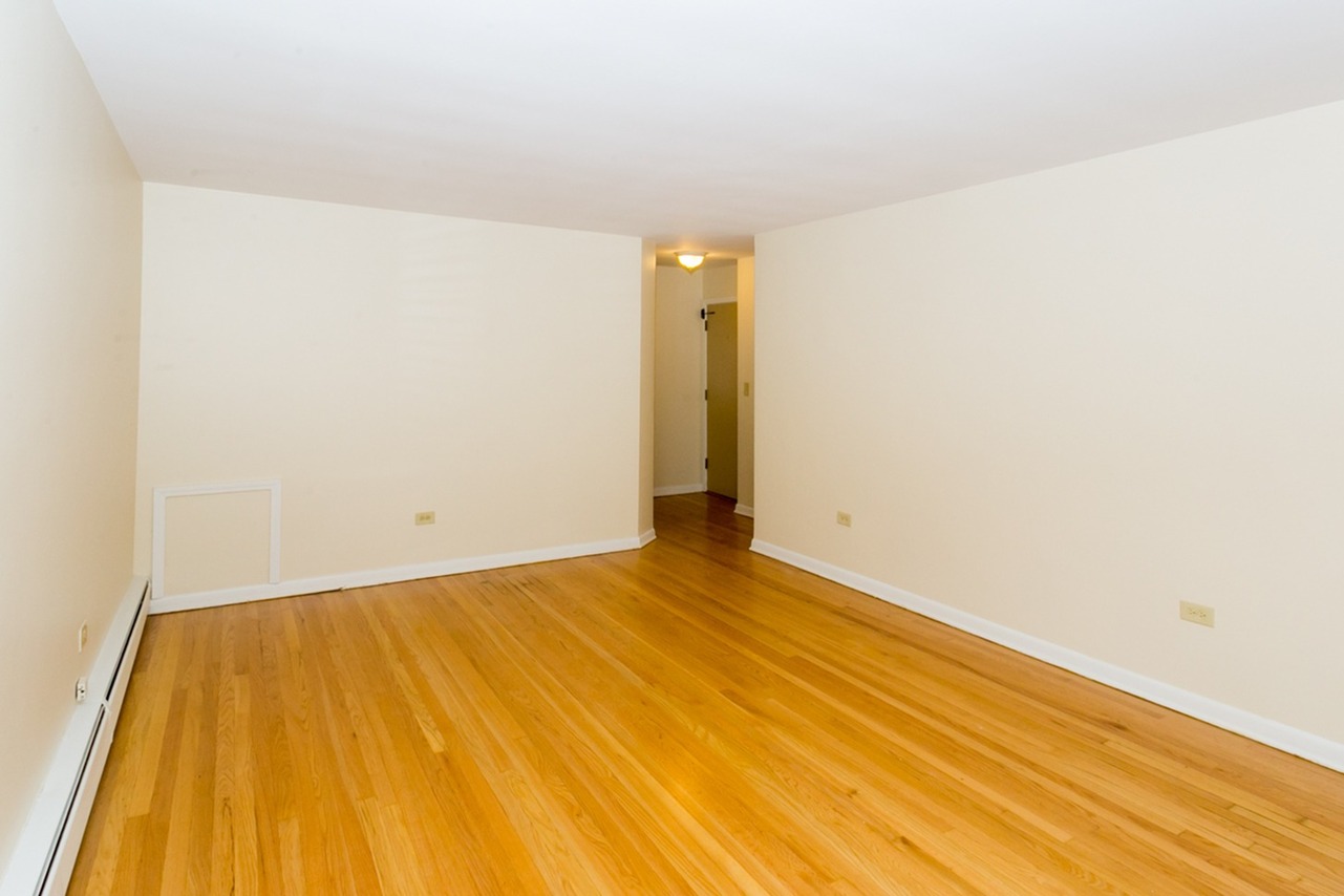 Light hardwood floor in a living room with off white walls and white trim.