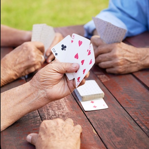 Seniors playing cards on a picnic table.
