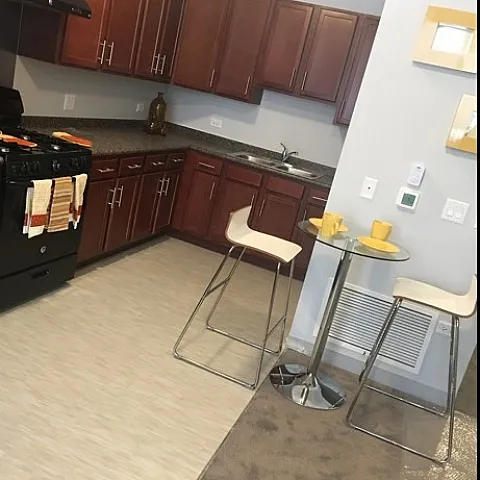 A kitchen with wood cabinets, black appliances and an eating area.