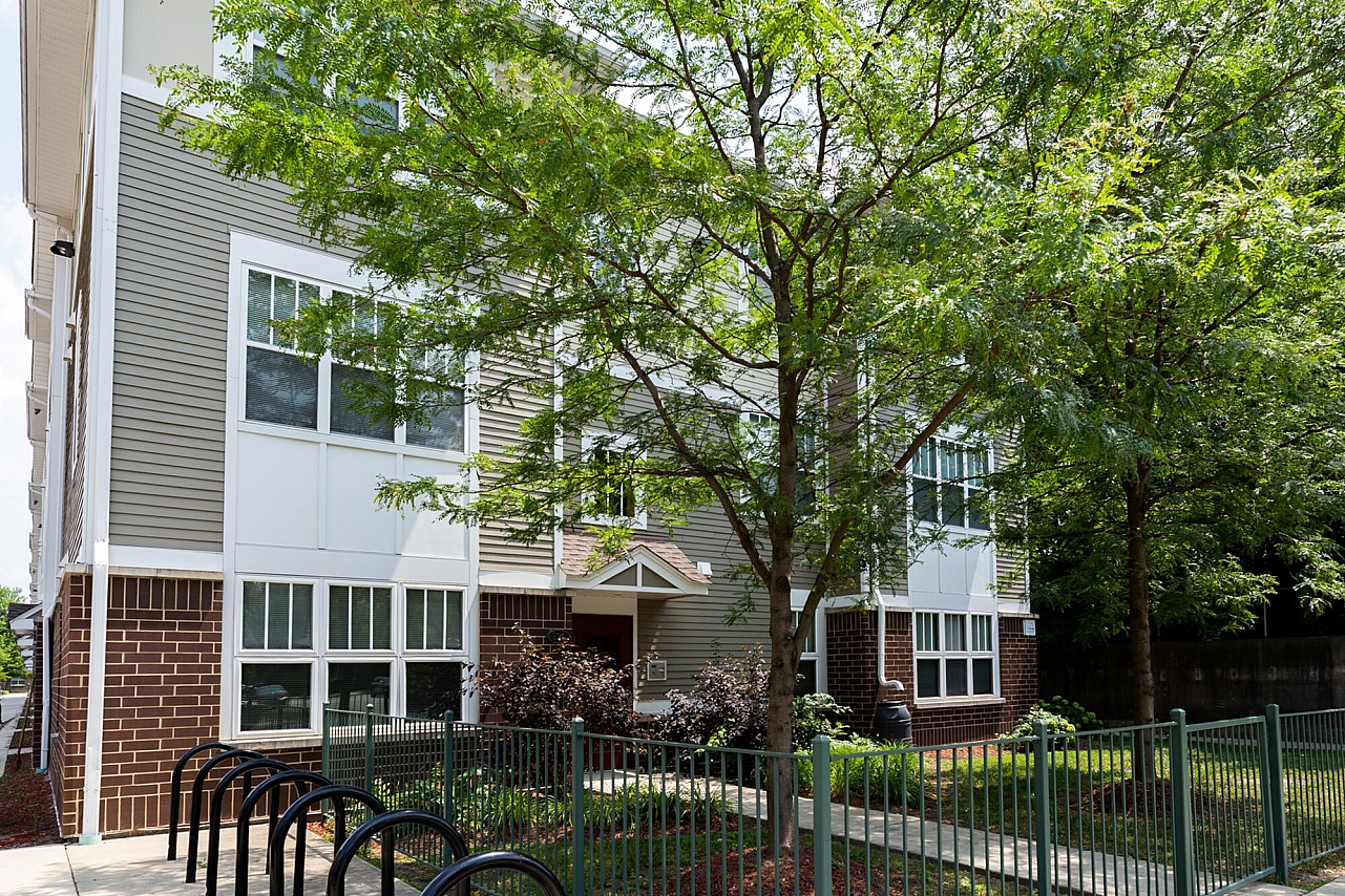 Exterior of Independence Apartments, a three story brown brick and gray sided townhouse style apartment building.