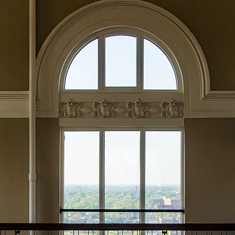 A vintage round top window on the 15th floor of the Nichols Tower looking outside.