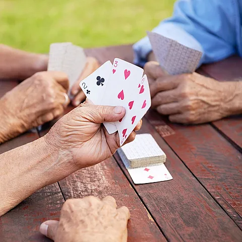 Seniors hands holding cards paying a card game