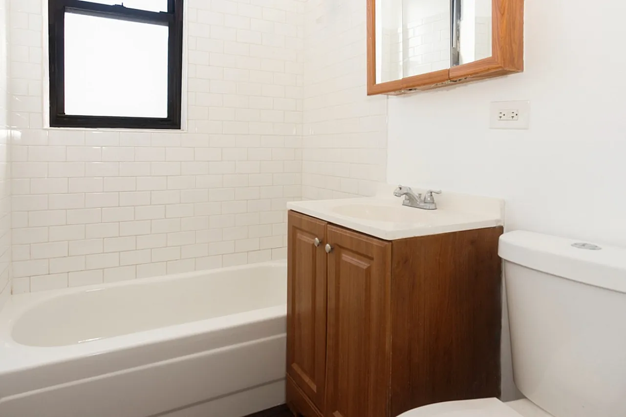 Bathroom with white tile surround and natural wood vanity and medicine chest