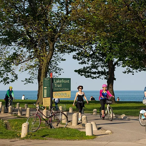 People walking and riding bikes on a paved trail along Lake Michigan