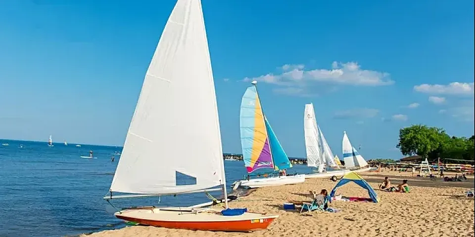 Evanston beach with sailboats on the shoreline under a bright blue sky.