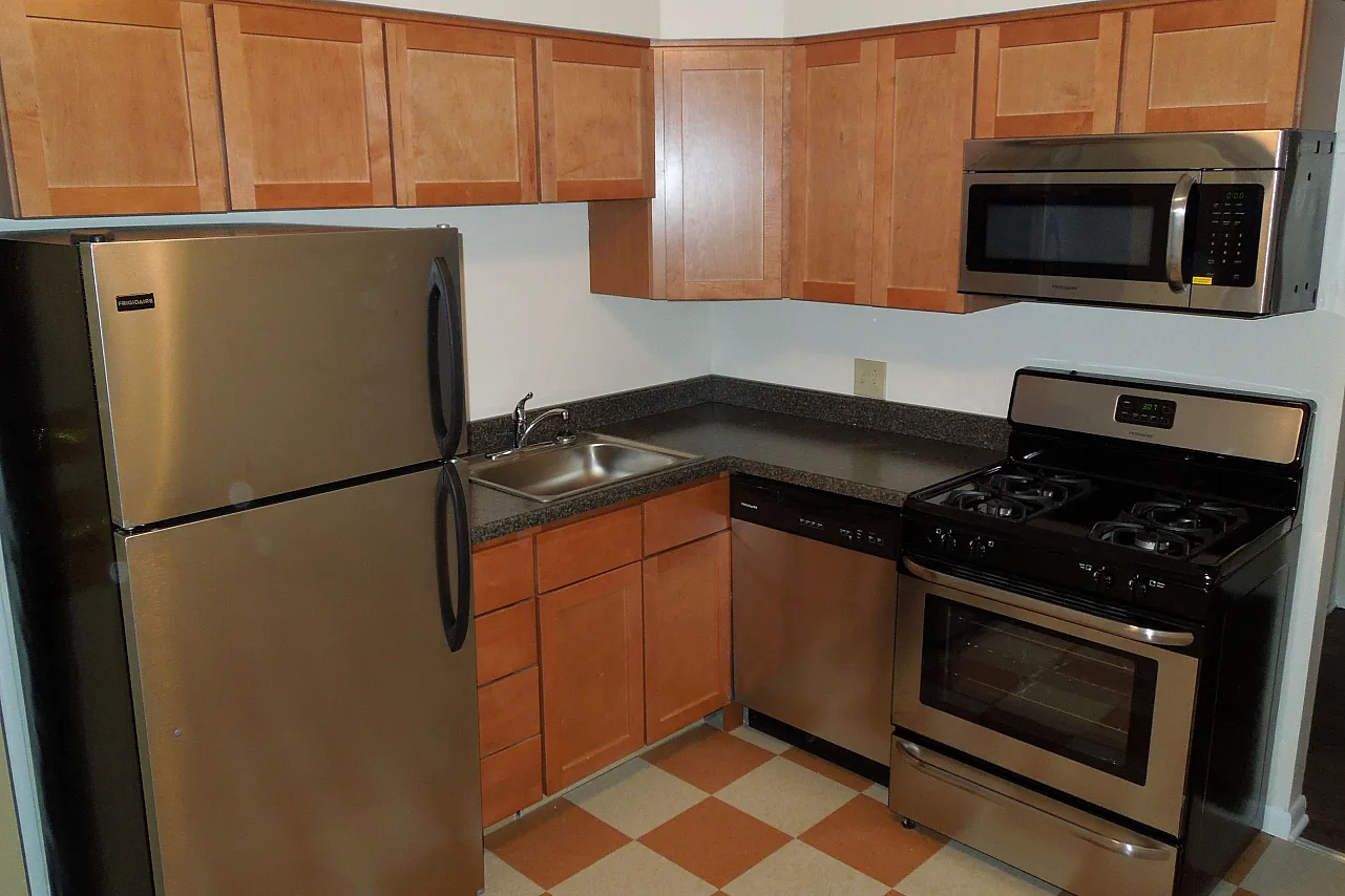 Kitchen with checked floor wood cabinets and stainless appliance