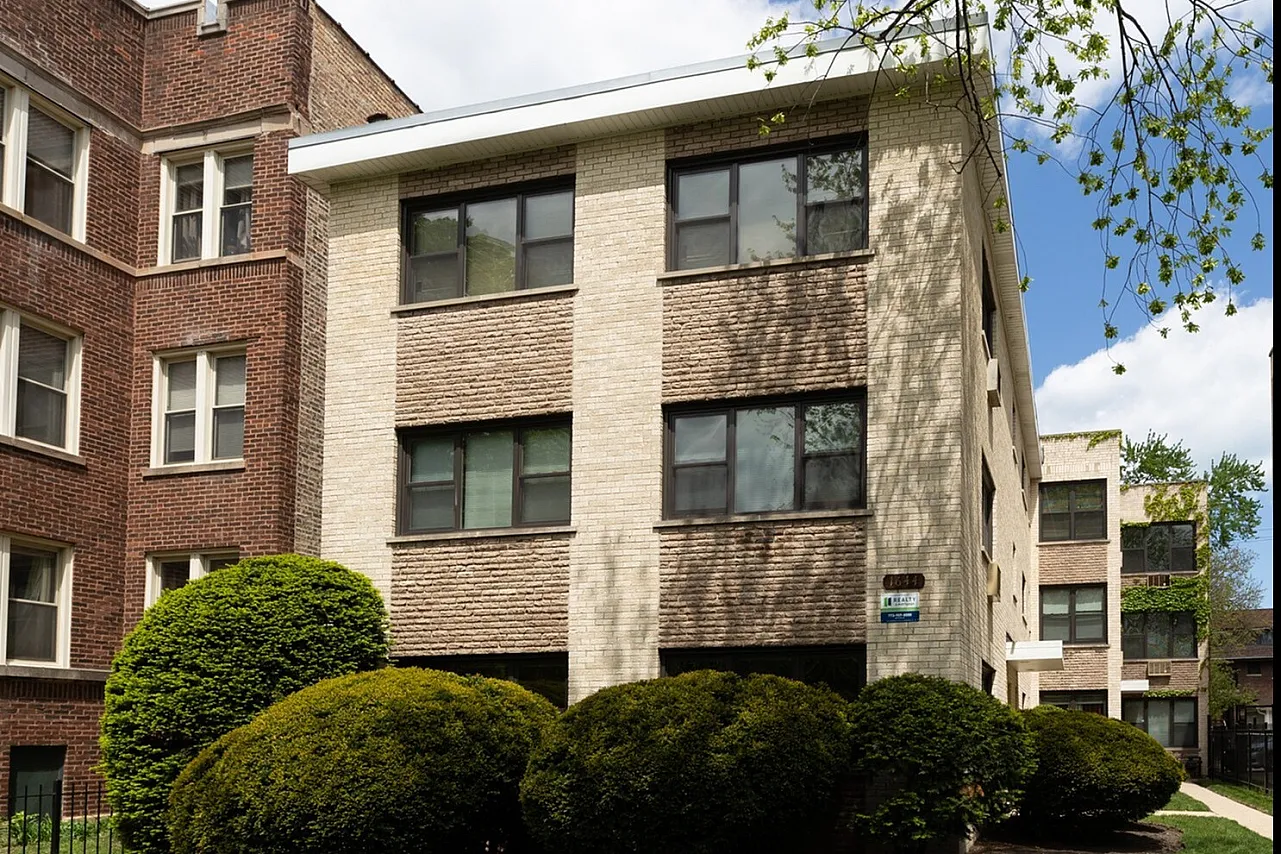 Exterior of 1644 West Sherwin a twelve unit mid century property with a yellow brick exterior and a landscaped front yard in Rogers Park.