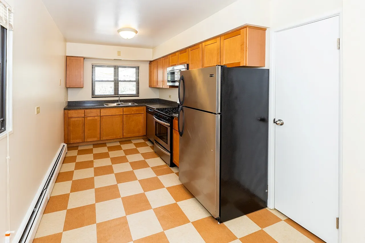 Galley styly kitchen with stainless appliances wood cabinets and checkered floor