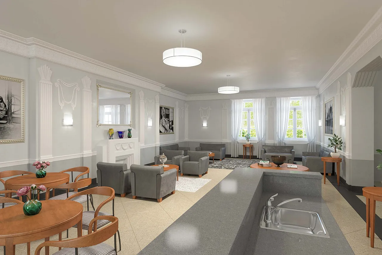 Nicely appointed community space with stuffed chairs, bright windows, a kitchenette, and grey walls with white trim.