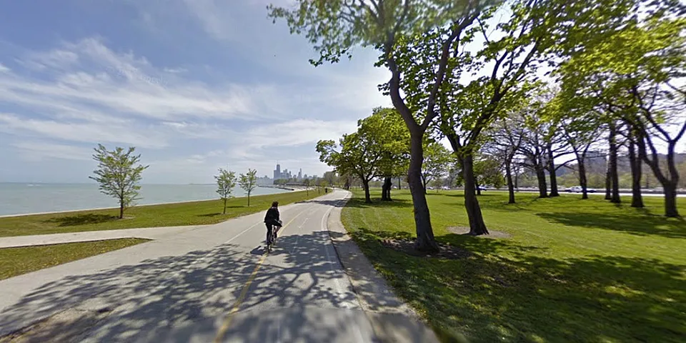 A paved bike path along Lake Michigan under a blue sky.