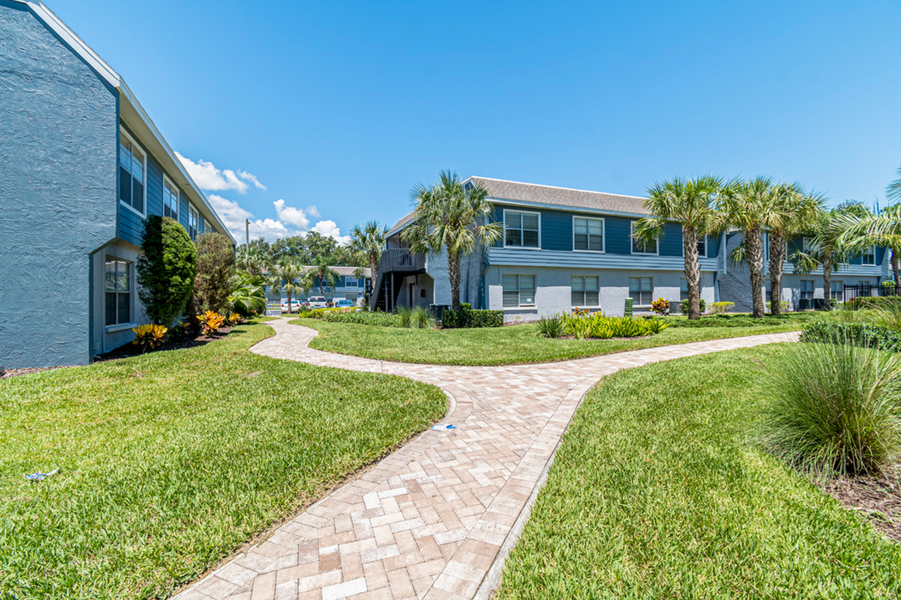 Exterior of apartment with lush landscaping,  palm trees, sidewalk andlandscaping