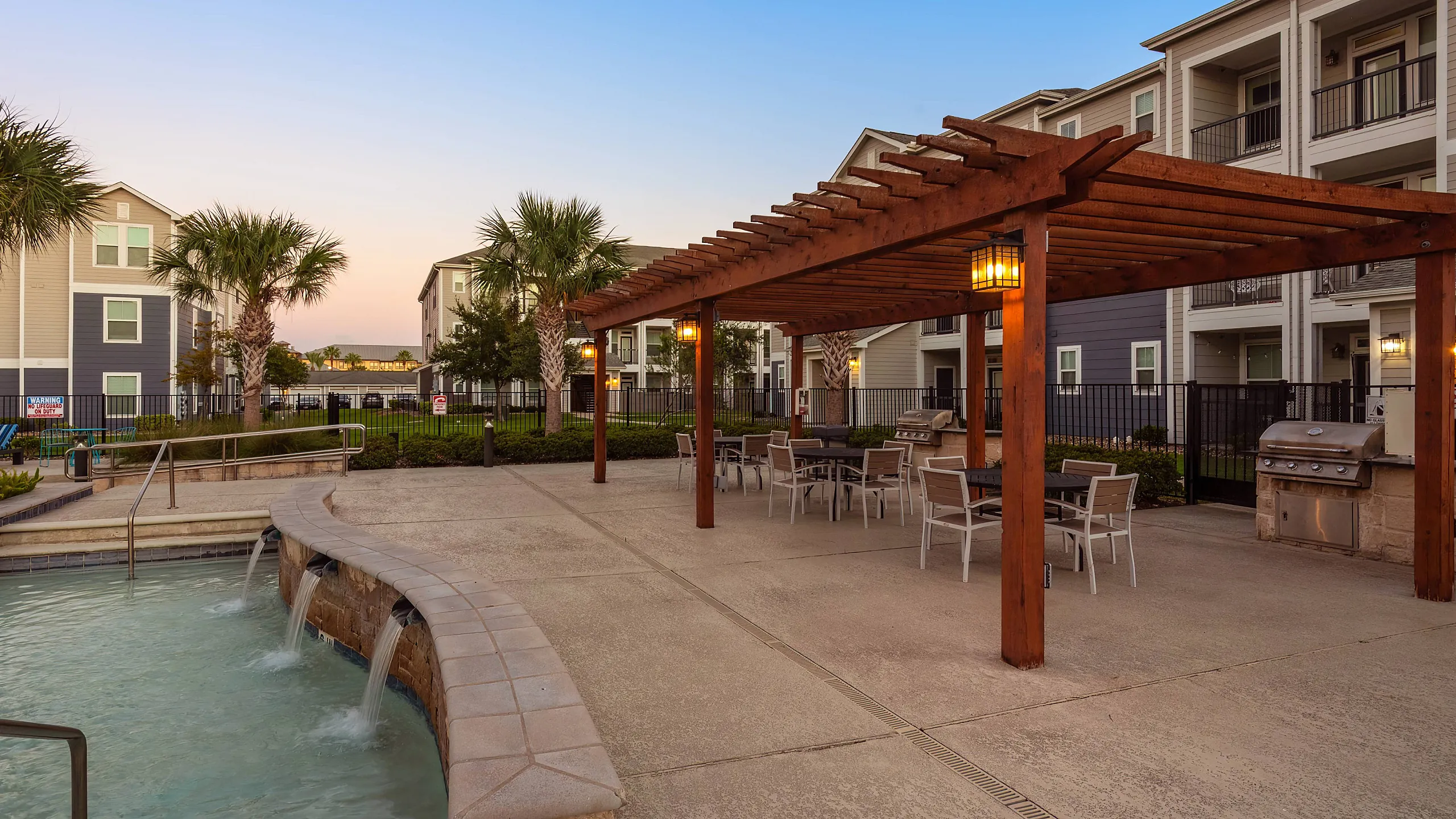 outdoor grill with shaded seating beside the pool