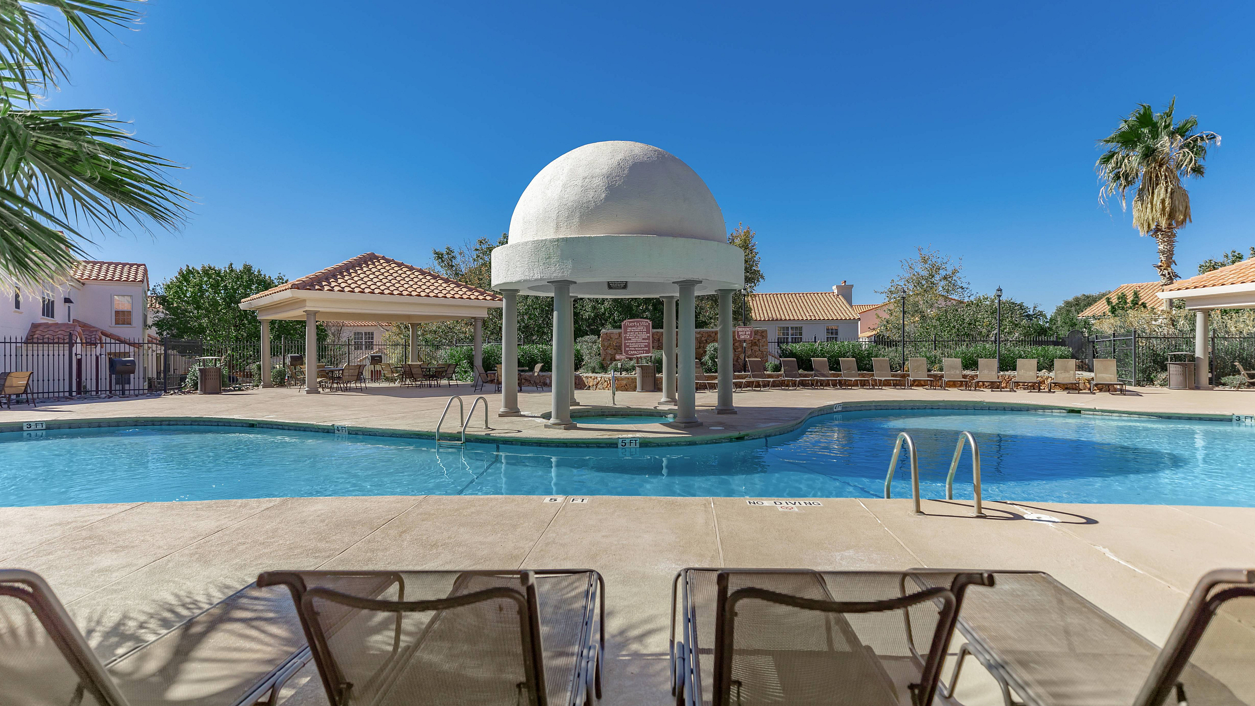 sparkiling pool with lounge seating and shaded hot tub