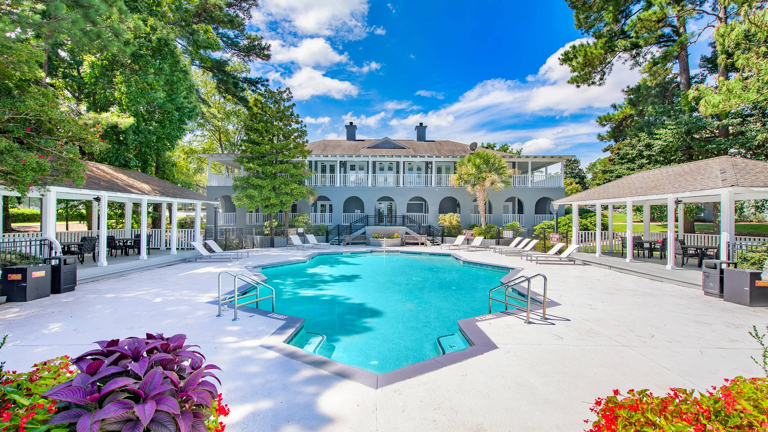 Sparkiling swiming pool with shaded seating area and outdoor grill beside the clubhouse