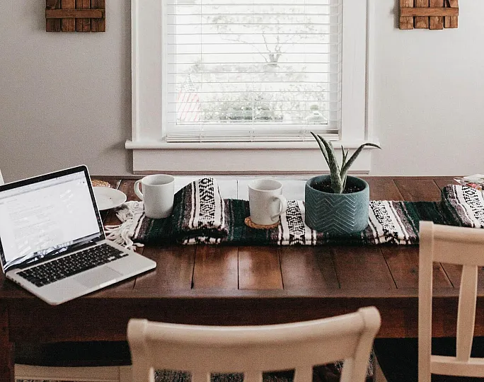 stock image of an office at the kitchen table with coffee and a plant