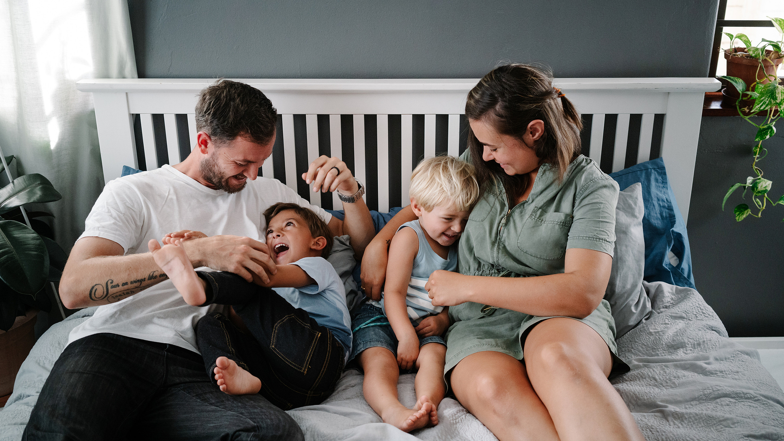 stock image of a young family playing on top of a bed