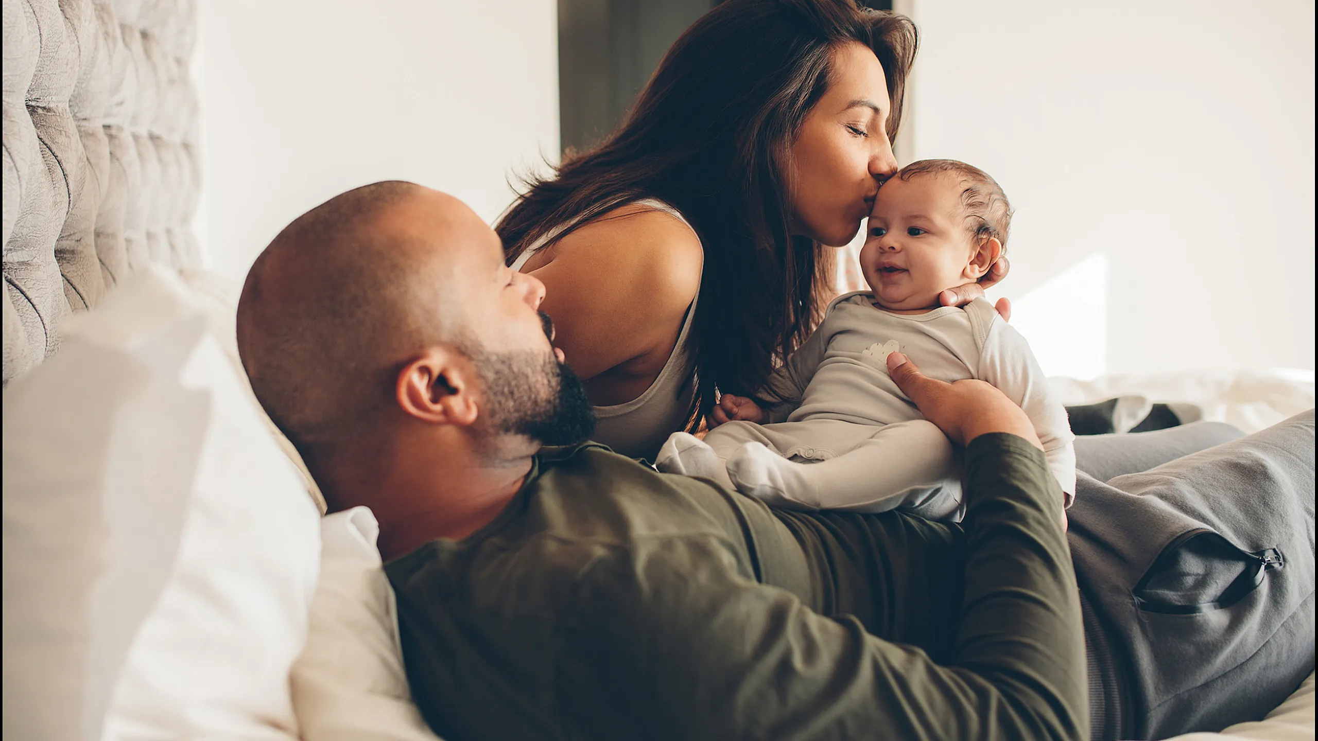 Stock of a family interacting on a bed with young baby