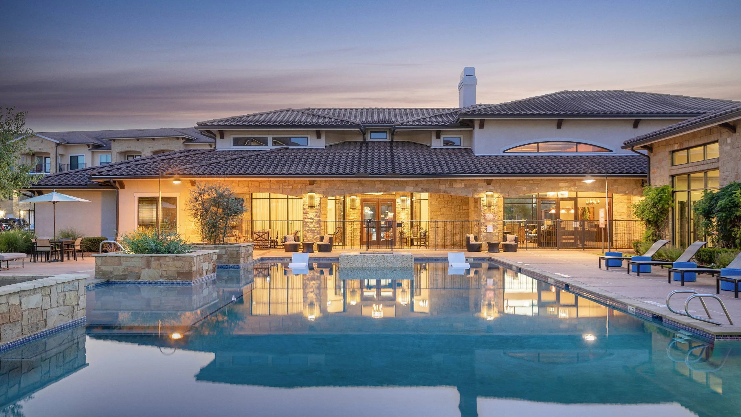 inviting clubhouse illuminated over the pool at dusk