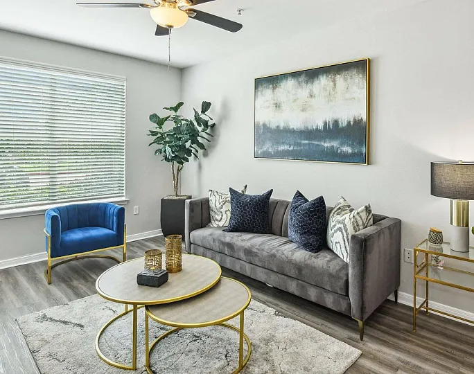 spacious living area in unit with ceiling fan and wood inspired flooring