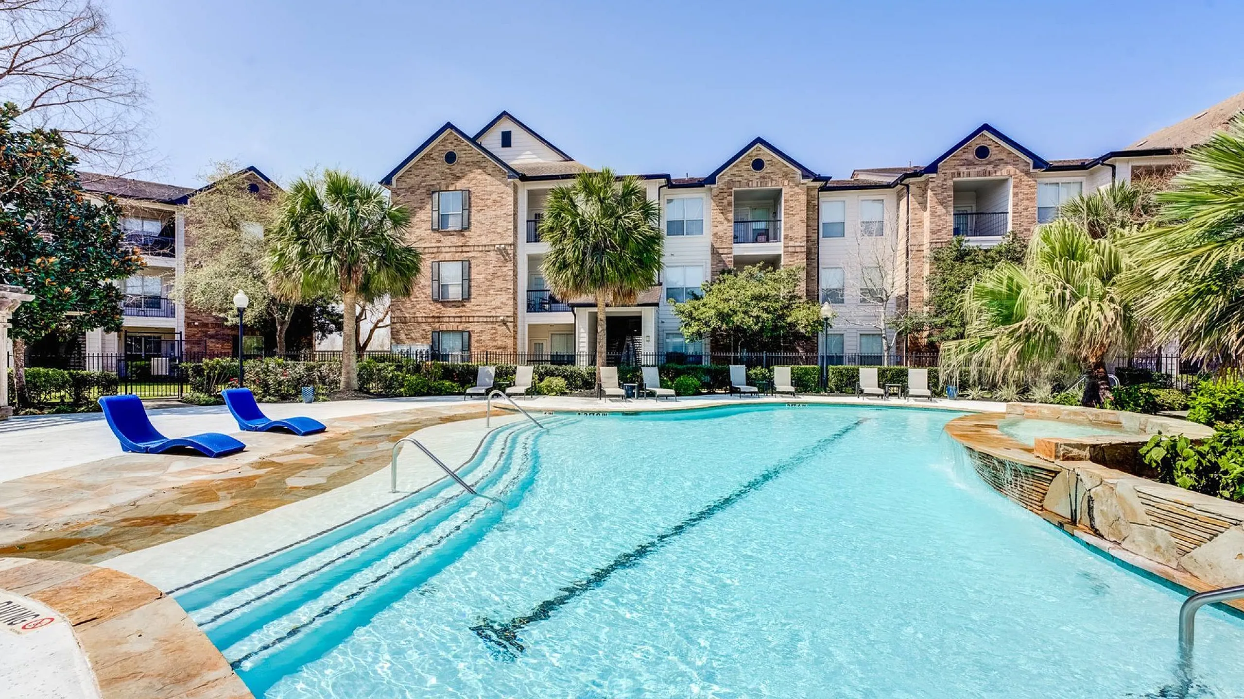 beautiful brick apartment buildings beside the sparkilng pool and landscaping