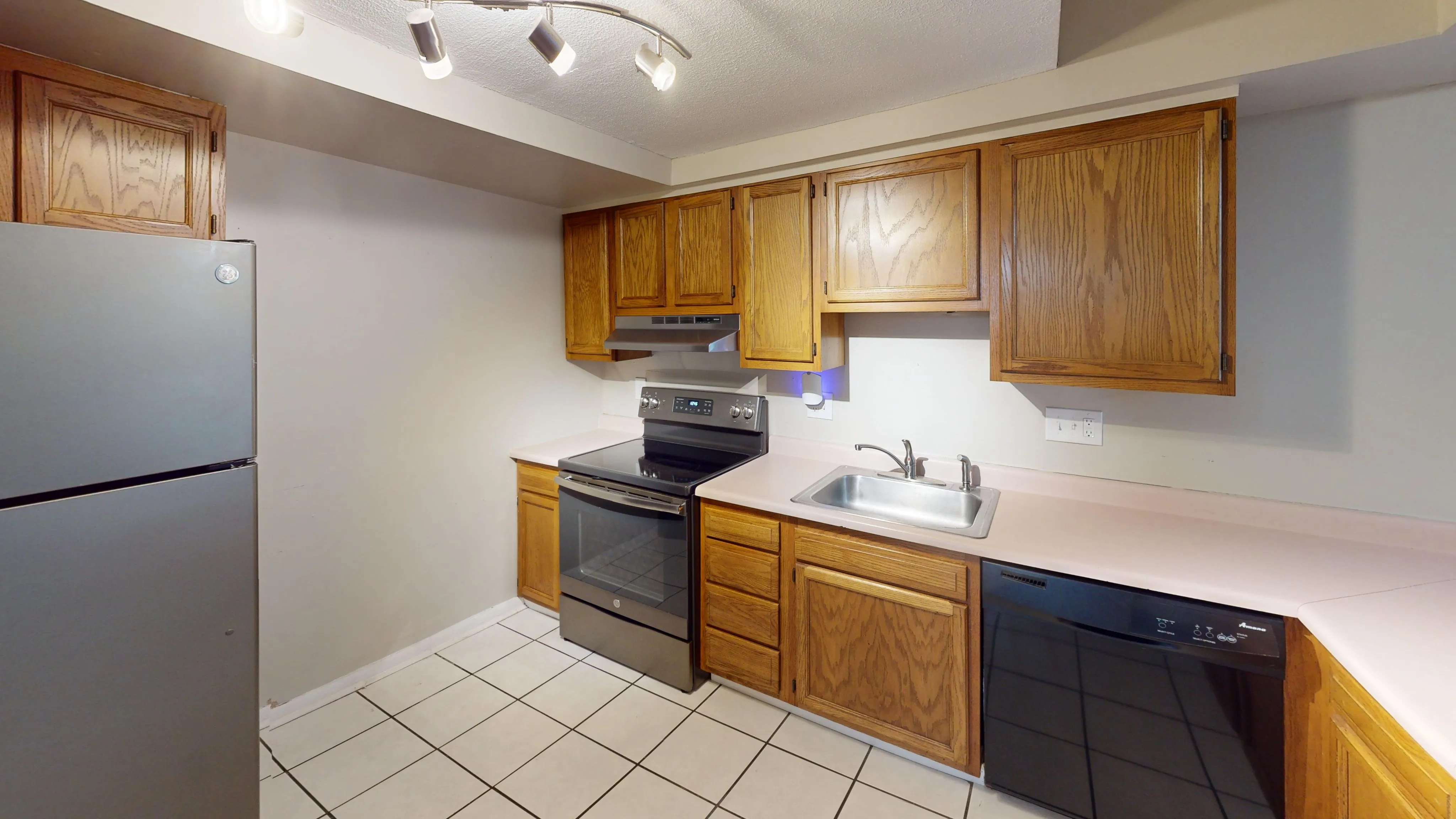 Well-appointed kitchen with wooden cabinetry, modern appliances, and tiled flooring.