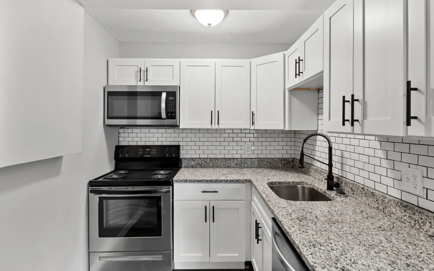 Chic kitchen with white cabinetry, stainless steel appliances, and granite countertops.