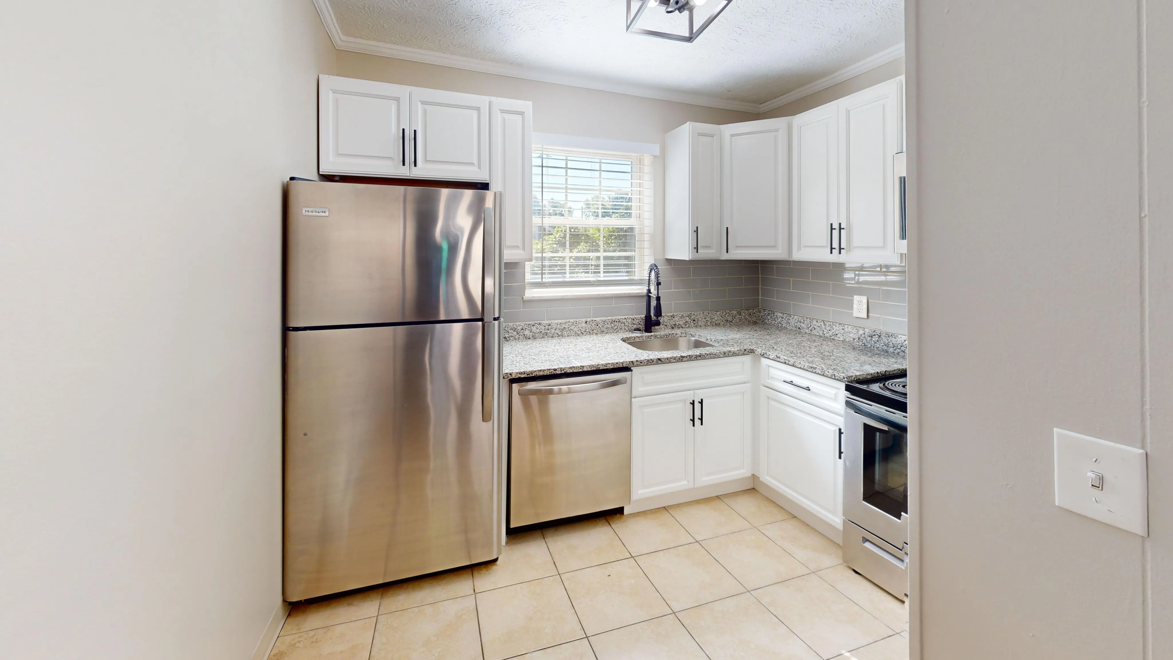 Modern kitchen with stainless steel appliances, white cabinetry, and granite countertops.