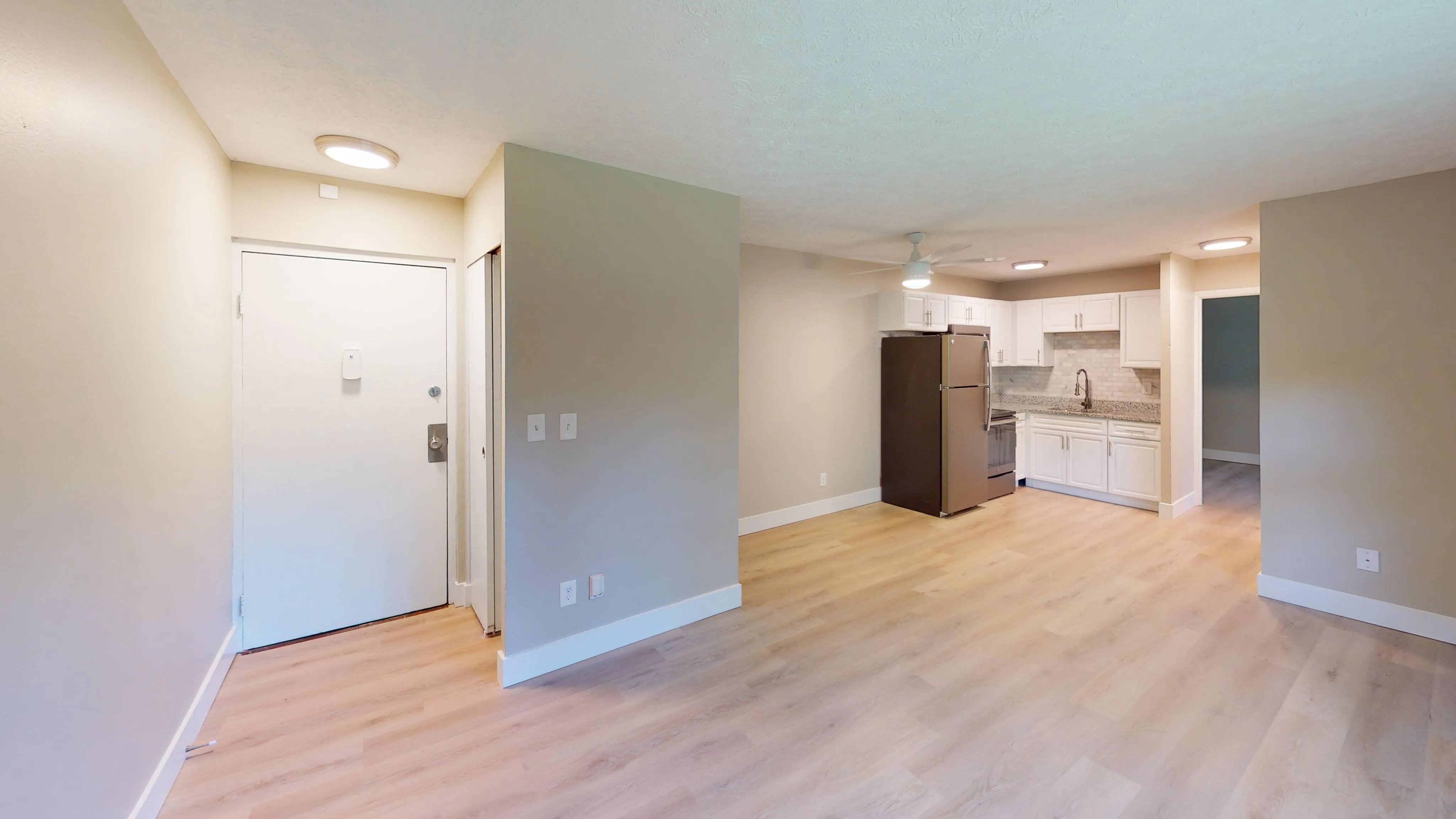 Bright open kitchen with white cabinets, modern appliances, and expansive hardwood flooring.